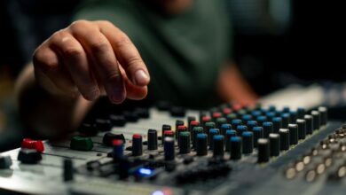 A close-up of an audio mixing console device used by someone working as a sound engineer in a music studio.