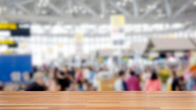 An open wooden surface in the foreground with an abstract blur of convention visitors and vendor booths in the background.