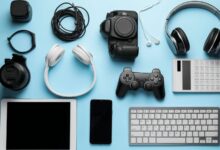 A collection of devices, including a gaming controller, headphones, a tablet, and a phone, arranged on a blue surface.