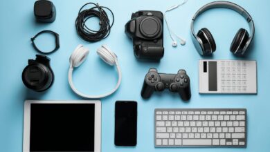 A collection of devices, including a gaming controller, headphones, a tablet, and a phone, arranged on a blue surface.