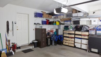A home garage with white walls and multiple boxes, containers, and tools placed on the right side against the wall.